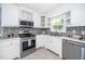 Well-lit kitchen featuring stainless steel appliances, white cabinets, and tile backsplash at 518 Buck Branch Dr, Garner, NC 27529