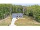 Aerial view showcasing a lovely blue home nestled among trees with a driveway and landscaped yard at 5550 Mountain Trl, Snow Camp, NC 27349