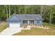 Charming blue home featuring a manicured front yard, garage, and inviting front porch with rocking chairs at 5550 Mountain Trl, Snow Camp, NC 27349