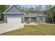 Inviting blue home featuring a garage, cozy front porch with chairs, and well-maintained lawn at 5550 Mountain Trl, Snow Camp, NC 27349