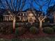 Elegant brick home with manicured front yard, columns, and mature trees, captured at dusk showcasing sophisticated curb appeal at 5768 Cavanaugh Dr, Raleigh, NC 27614