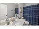 Well-lit bathroom featuring a shower with a patterned curtain, a sink, and a mirror at 6313 Kayton St, Raleigh, NC 27616