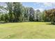 Expansive backyard featuring lush green grass, mature trees, and a white garden structure at the rear at 6553 Vintage Ridge Ln, Fuquay Varina, NC 27526