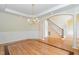 Formal dining room featuring hardwood floors, wainscoting, a decorative chandelier, and adjacent staircase at 6553 Vintage Ridge Ln, Fuquay Varina, NC 27526
