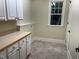 Well-lit laundry room with tile flooring, cabinets, countertop, and a window with natural light at 6553 Vintage Ridge Ln, Fuquay Varina, NC 27526