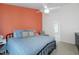 Comfortable bedroom with blue bedding, a ceiling fan, a chair, and an accent wall with an orange color at 6924 Coventry Ridge Rd, Raleigh, NC 27616