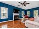 Comfortable living room with a fireplace, hardwood floors, ceiling fan, and large windows for natural light at 6924 Coventry Ridge Rd, Raleigh, NC 27616