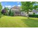 Expansive backyard with lush green lawn and mature trees, showcasing the screened porch of the home at 900 Green Oaks Pkwy, Holly Springs, NC 27540