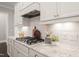 Granite countertops accent the white cabinetry, stainless vent hood, and white subway tile backsplash at 900 Green Oaks Pkwy, Holly Springs, NC 27540