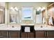 Well lit bathroom with double sinks, wood cabinets, vanity, and a shower reflected in the mirrors at 9300 Lake Wheeler Rd, Fuquay Varina, NC 27526