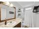 Well-lit bathroom boasts a neutral color palette, vanity with wood framed mirror, and a shower with a white curtain at 9300 Lake Wheeler Rd, Fuquay Varina, NC 27526