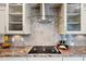 Modern kitchen cooktop with glass vent hood, sleek backsplash, and cream colored cabinets at 9300 Lake Wheeler Rd, Fuquay Varina, NC 27526