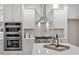 Modern kitchen with a stainless steel hood, double oven and quartz countertops at 9425 Brimstone Ln, Raleigh, NC 27613
