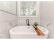 Luxurious bathtub with marble tile surround and a tray for bath essentials at 104 Crosby Ln, Sanford, NC 27330