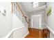 Bright foyer with hardwood floors, stairs with white railing, transom windows, and wainscotting at 106 Roundtop Rd, Cary, NC 27519