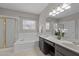 Bathroom featuring a large tub, shower with gold trim, double sinks, and a large mirror at 107 Covington Dr, Chapel Hill, NC 27514