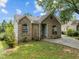 Charming brick home featuring arched windows, a round window, and mature landscaping at 107 Covington Dr, Chapel Hill, NC 27514