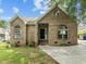Charming brick home featuring arched windows, a round window, and mature landscaping at 107 Covington Dr, Chapel Hill, NC 27514