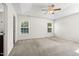 Bright bedroom features neutral carpet, fan, and well-lit windows with views of the exterior landscape at 109 Citrine Ct, Durham, NC 27703
