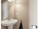 Stylish half bathroom features a pedestal sink, sleek faucet, and modern lighting at 110 Bray Dr, Mebane, NC 27302