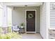 Inviting front porch features a seating area and a welcoming wreath on the dark front door at 110 Bray Dr, Mebane, NC 27302