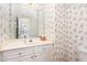 Bathroom with floral wallpaper, cream vanity with cabinets and drawers, along with large mirror at 11005 Louson Pl, Raleigh, NC 27614