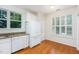 Bright kitchen features white appliances, granite counters, and hardwood floors and a window looking out into the yard at 11005 Louson Pl, Raleigh, NC 27614