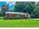 Attractive brick home with a metal roof, carport, mature trees and a vibrant green lawn at 111 Dee Long Rd, Roxboro, NC 27574
