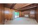 Spacious living room with wood-paneled walls, a brick fireplace, and sliding glass doors to a deck at 1116 Little Creek Rd, Durham, NC 27713