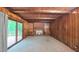 An inviting living room showcasing wood-paneled walls, a cozy brick fireplace, and access to a deck through glass doors at 1116 Little Creek Rd, Durham, NC 27713