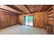 A spacious living room with warm wood-paneled walls, a charming brick fireplace, and deck access via glass doors at 1116 Little Creek Rd, Durham, NC 27713