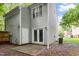 A view of the back of the house, showing an exterior door, a patio area, and lush surrounding greenery at 118 Rhum Pl, Garner, NC 27529