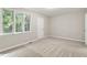 A bright bedroom featuring a large window, fresh paint, and soft neutral carpeting at 118 Rhum Pl, Garner, NC 27529