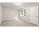 Light-filled bedroom with neutral carpet, a bright window, and a white door at 118 Rhum Pl, Garner, NC 27529