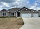 New single-story home featuring a 3-car garage, neutral siding, and an open front yard with fresh sod at 120 Newport Lndg # 99, Garner, NC 27529