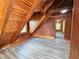 An attic bedroom has wood beams, wood walls, and light-colored flooring at 1283 Ennis Rd, Angier, NC 27501