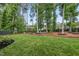 Well-maintained backyard featuring a lush green lawn, mature trees, and landscaping at 1324 Sandybrook Ln, Wake Forest, NC 27587