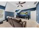 Spacious bonus room with blue walls, a ceiling fan, and a large screen TV for entertainment at 1324 Sandybrook Ln, Wake Forest, NC 27587