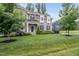 Charming two-story home surrounded by a lush green lawn, mature trees, and manicured landscaping at 1324 Sandybrook Ln, Wake Forest, NC 27587