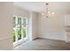 Bright dining room featuring wood-look floors, wainscoting, a modern chandelier, and a window overlooking the yard at 137 Wintermist Dr, Cary, NC 27513