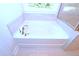 Close-up of a pristine white bathtub under a window, complemented by light-colored tile flooring at 1441 Rosepine Dr Dr, Cary, NC 27519