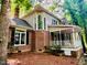 Charming brick home featuring a covered porch, large windows, and lush landscaping offering a serene and inviting outdoor space at 1512 Cumberland Rd, Chapel Hill, NC 27514