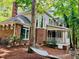 A beautiful home with a brick facade, large windows, and a covered porch, surrounded by lush greenery and a relaxing hammock at 1512 Cumberland Rd, Chapel Hill, NC 27514