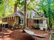 A beautiful home with a brick facade, large windows, and a covered porch, surrounded by lush greenery and a relaxing hammock at 1512 Cumberland Rd, Chapel Hill, NC 27514