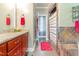Bright bathroom featuring granite countertops, cherry cabinets, a large mirror, and a tile shower at 1770 Gentry Ridge Rd, Roxboro, NC 27574