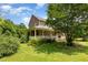 View of the brick home with a large wrap-around porch and beautifully landscaped yard at 1770 Gentry Ridge Rd, Roxboro, NC 27574