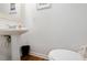 Bright half bathroom with a pedestal sink, a white toilet, and light wood-look flooring at 1824 Vintage Rd, Raleigh, NC 27610