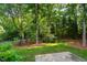 Backyard with mature trees, lush green lawn and stone patio at 209 Bailey Ridge Dr, Morrisville, NC 27560
