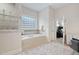 Bathroom featuring soaking tub, glass block window, white tile, and view to bedroom at 209 Bailey Ridge Dr, Morrisville, NC 27560
