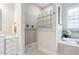 Bathroom featuring walk-in shower with glass blocks, soaking tub, and white vanity at 209 Bailey Ridge Dr, Morrisville, NC 27560